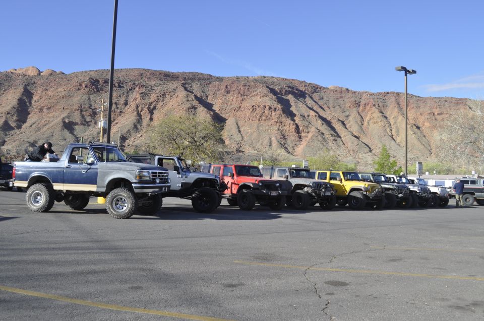 Blue and silver Ford Bronco with lifted suspension and off-road tires, parked in a lot with other vehicles