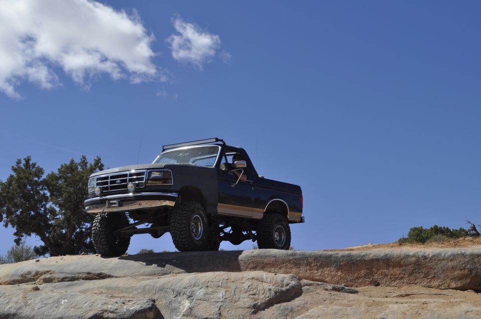 Dark blue lifted 1991 Ford Bronco on rocky terrain under a blue sky
