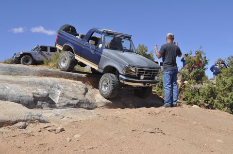 1991 Ford Bronco - A two-tone Ford Bronco navigates a rocky trail with another vehicle in the background.