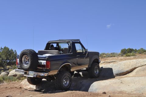 1991 Ford Bronco - 1991 Ford Bronco navigating rocky terrain under a clear blue sky.