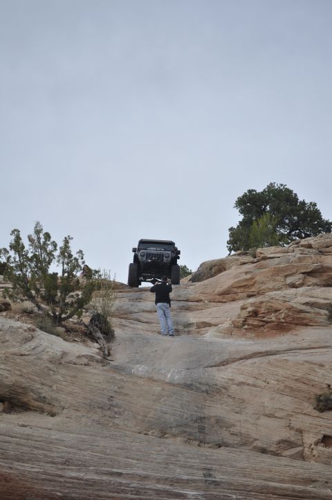 1991 Ford Bronco - Jeep Wrangler being lifted by a person on a rocky trail.
