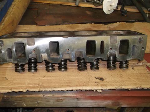 1964 Ford Galaxie - Engine cylinder head with valve springs shown on a wooden surface.