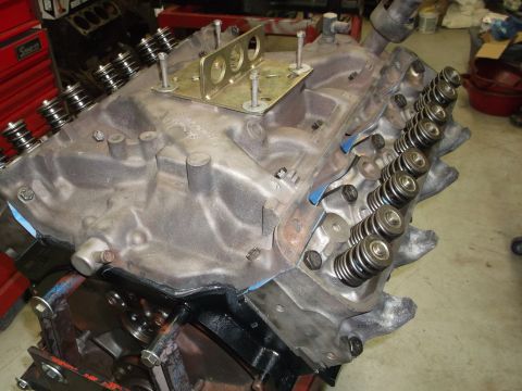 1964 Ford Galaxie - Close-up view of an engine block, showing valve springs and a metal plate bolted to the intake manifold mounting surface.
