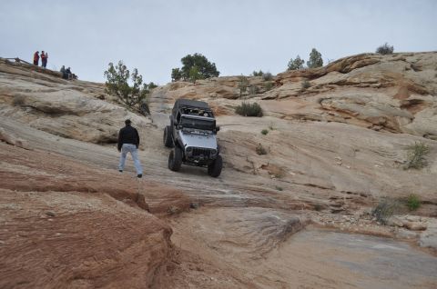 1991 Ford Bronco - Jeep Wrangler navigates a challenging off-road course in a desert landscape.