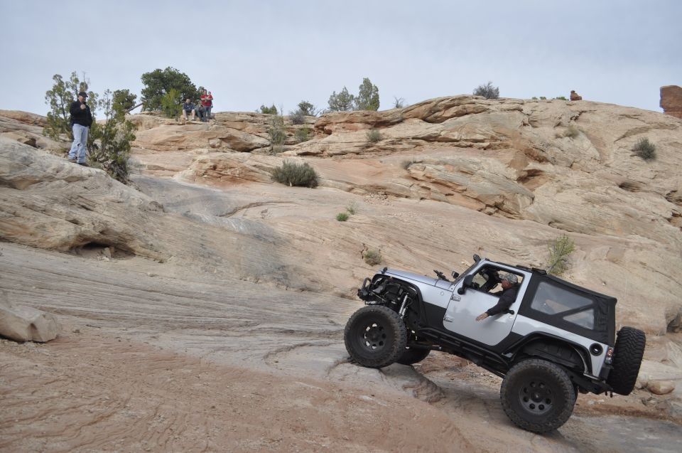 Silver Jeep Wrangler climbing rocky terrain