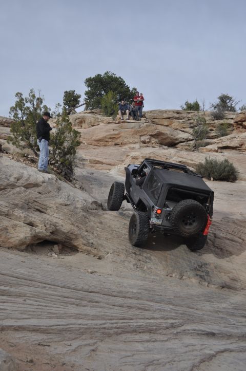 1991 Ford Bronco - Off-road vehicle navigates challenging rocky terrain with spectators observing the ascent.