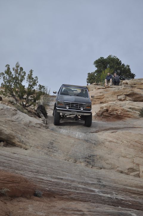 1991 Ford Bronco - 1991 Ford Bronco navigates a challenging rocky incline in a desert landscape.