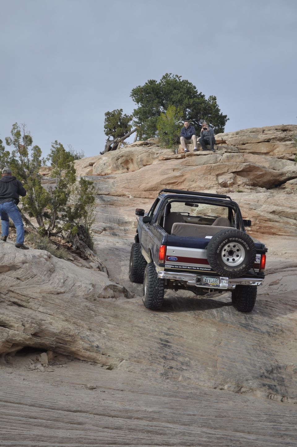 Ford Bronco climbing a rocky hill with people watching from above