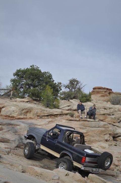 1991 Ford Bronco - A Ford Bronco navigates a challenging rocky trail with two people observing from above.