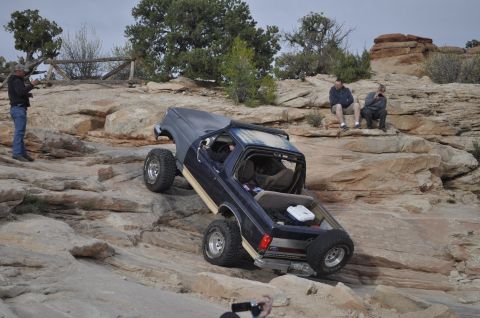 1991 Ford Bronco - A dark blue 1991 Ford Bronco navigates a challenging rocky incline in a desert landscape.