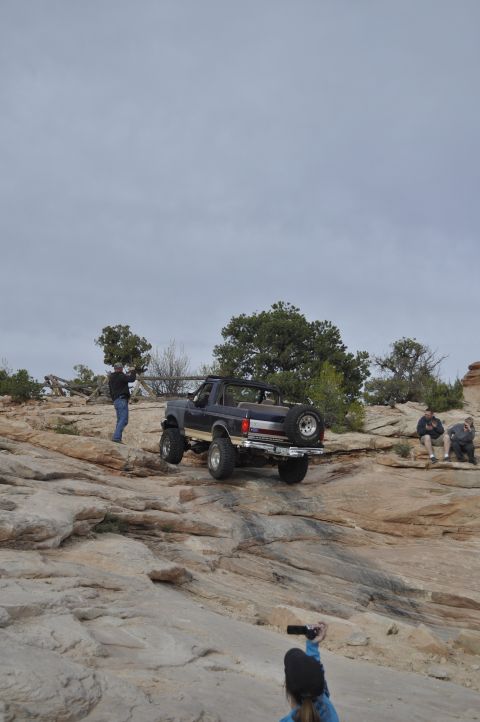 1991 Ford Bronco - A Ford Bronco navigates a rocky trail with onlookers observing the off-road adventure.