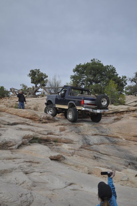 1991 Ford Bronco - A Ford Bronco navigates a rocky off-road trail with onlookers present.