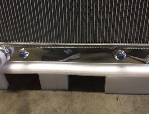 1978 Ford Bronco - A radiator part is shown in its packaging, with a reflection of a shoe in the chrome.