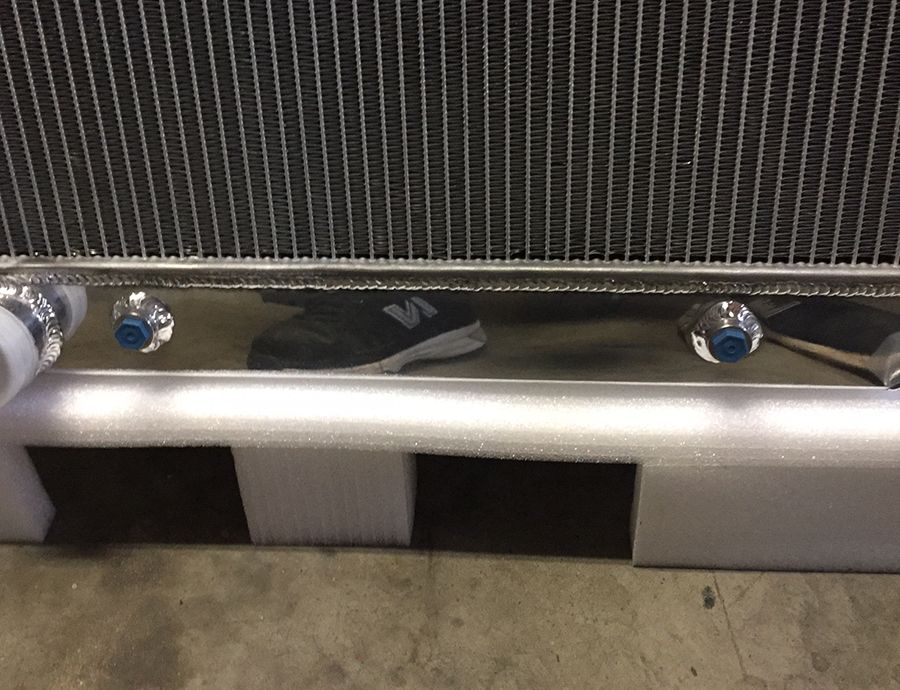 Radiator with chrome end tanks and blue fittings, resting on foam packaging