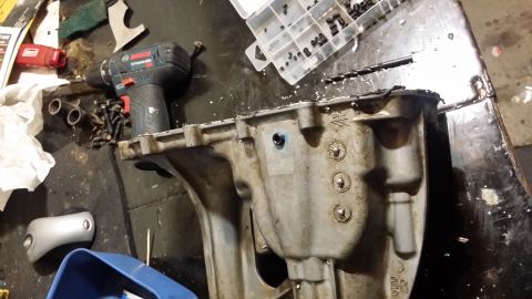 2007 Subaru Impreza - Close-up of a vehicle's oil pan with tools and parts scattered around on a workbench.
