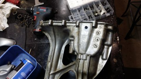 2007 Subaru Impreza - A close-up view of a greasy automotive component, possibly a transmission housing, with tools and fasteners scattered around.
