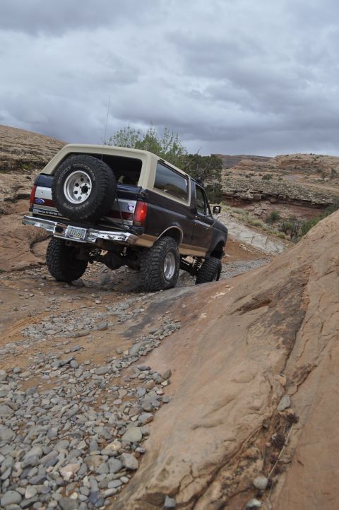 1991 Ford Bronco - Ford Bronco navigates a challenging off-road path in a desert landscape.