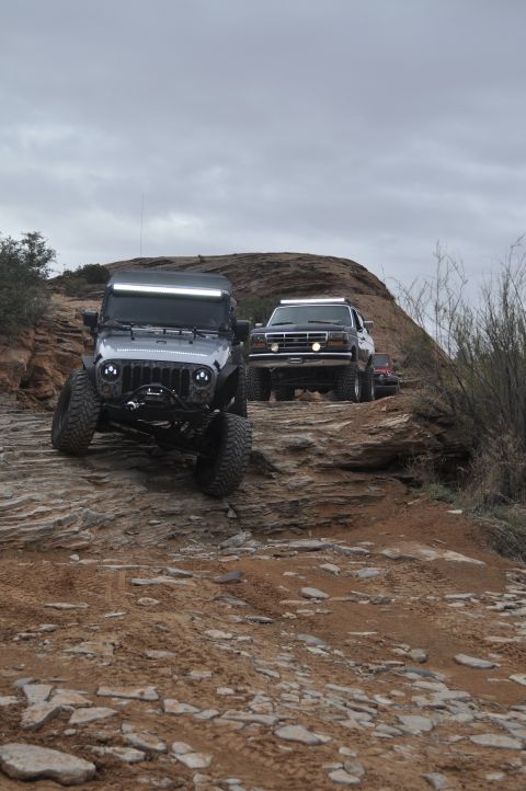 1991 Ford Bronco - Two off-road vehicles, a 1991 Ford Bronco and a Jeep Wrangler, navigate a rocky path.