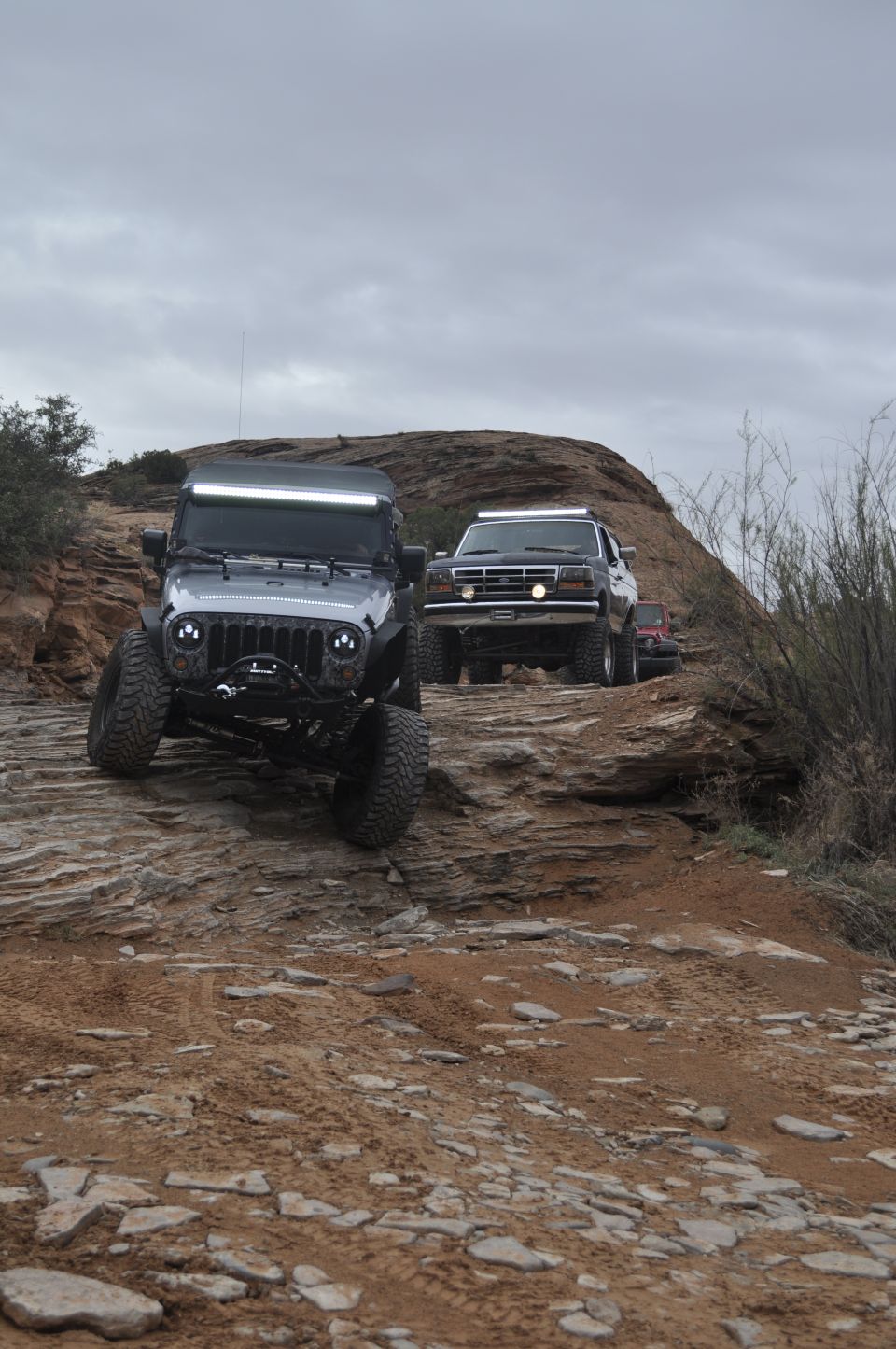 1991 Ford Bronco and a Jeep Wrangler driving on a rocky trail