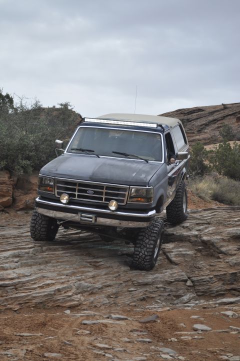 1991 Ford Bronco - A dark blue 1992 Ford Bronco navigates a rocky trail under a cloudy sky.