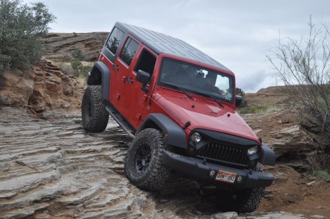 1991 Ford Bronco - A red Jeep Wrangler Rubicon navigates a challenging rocky trail, its off-road capabilities.