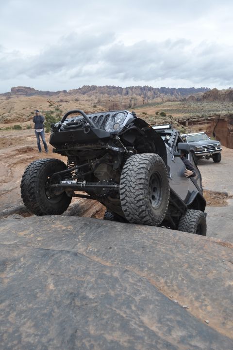 1991 Ford Bronco - A modified Jeep Wrangler navigates rocky terrain, with another vehicle in the background.