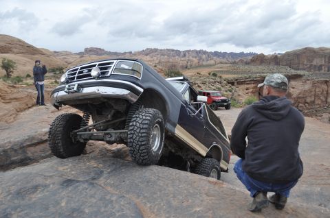 1991 Ford Bronco - A modified Ford Bronco navigates a rocky off-road trail with another vehicle in the background.