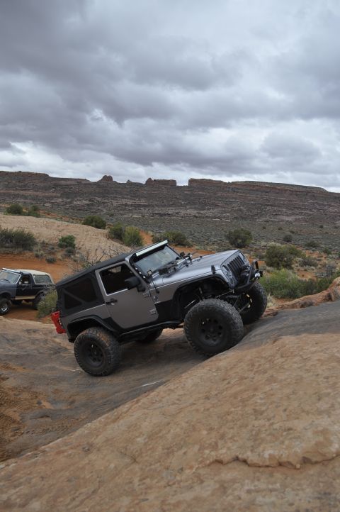 1991 Ford Bronco - Two off-road vehicles navigate a challenging rocky terrain under a cloudy sky.