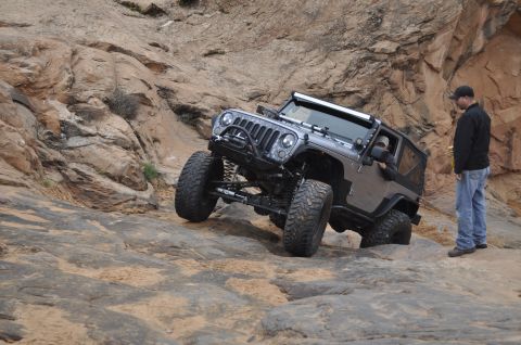 1991 Ford Bronco - Jeep Wrangler navigating a challenging rocky trail with a person observing.