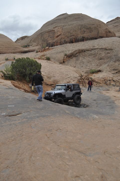 1991 Ford Bronco - A Jeep navigates a challenging off-road trail in a desert landscape.