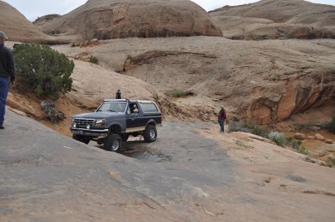 1991 Ford Bronco - A Ford Bronco navigates a challenging rocky terrain in a desert landscape.