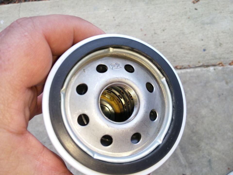 Hand holding an oil filter with a "22" stamped on it