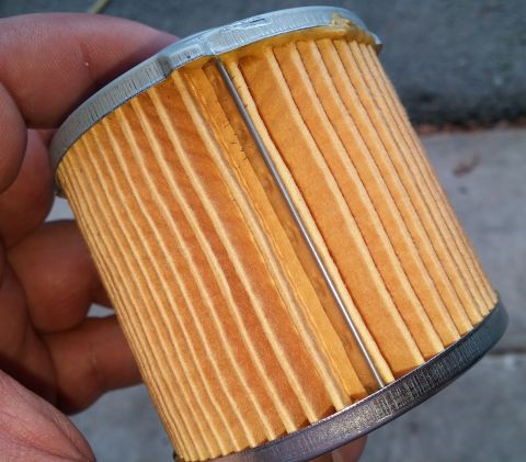 2000 Ford Crown Victoria - A hand holds an oil filter, its pleated paper element and metal end caps.
