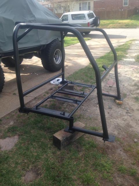 1972 Ford Bronco - A custom roll cage is shown in a driveway, with a covered vehicle and a white SUV in the background.