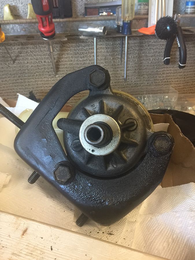 Black metal automotive part with bolts and a central shaft, resting on paper towels