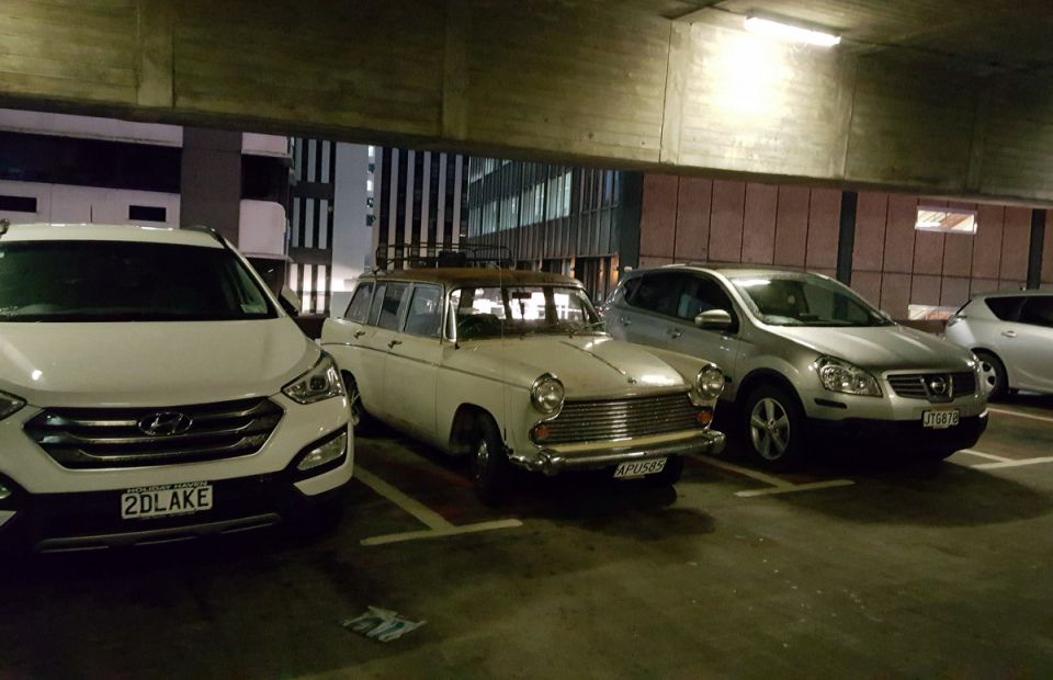 Vintage station wagon with roof rack parked in a lot next to a white SUV and a silver SUV