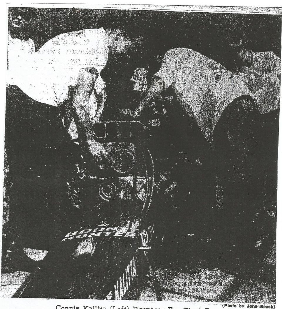 Black-and-white newsprint photo of crew working on Bounty Hunter dragster engine, Connie Kalitta at left