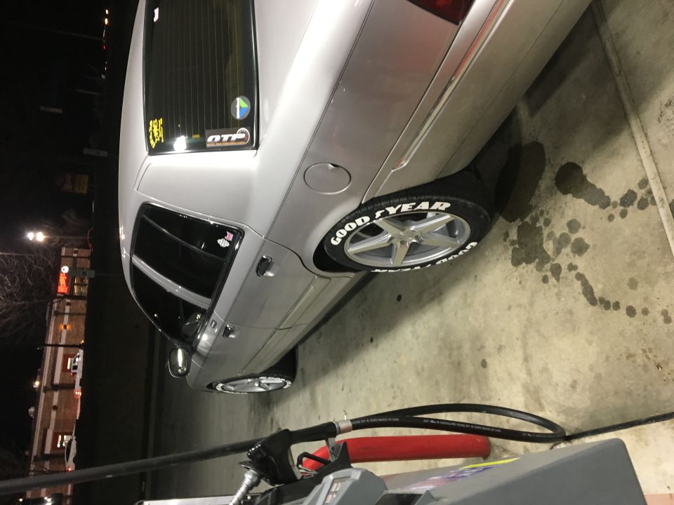 Silver sedan with white letter tires at a gas pump