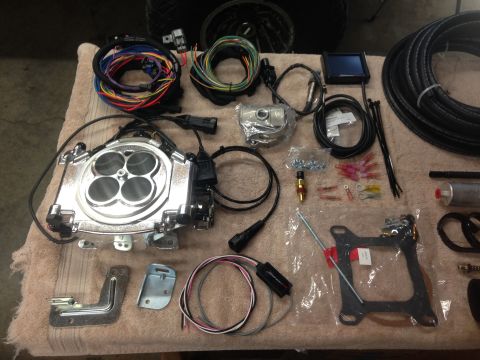1979 Ford Bronco - Holley Sniper EFI throttle body and associated installation components laid out on a cloth surface.