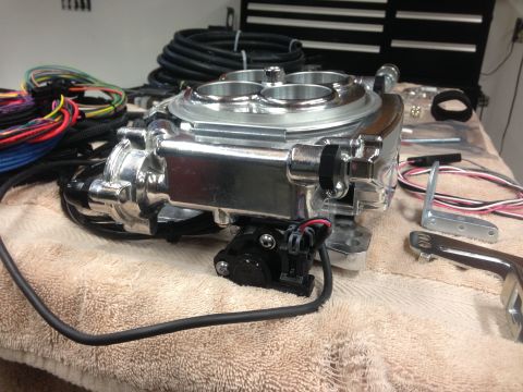 1979 Ford Bronco - A chrome fuel injection throttle body and associated wiring are laid out on a towel, ready for installation.