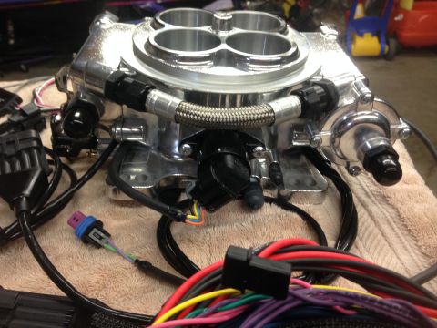 1979 Ford Bronco - Close-up of a Holley Sniper EFI throttle body, showing its polished finish and connected wiring harness.