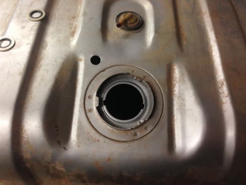 1979 Ford Bronco - This image shows the filler neck of a vehicle's fuel tank, which appears to be made of metal and shows signs of rust.