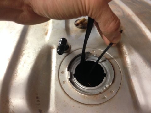 1979 Ford Bronco - A hand inserts a black gasket into the opening of a fuel tank.