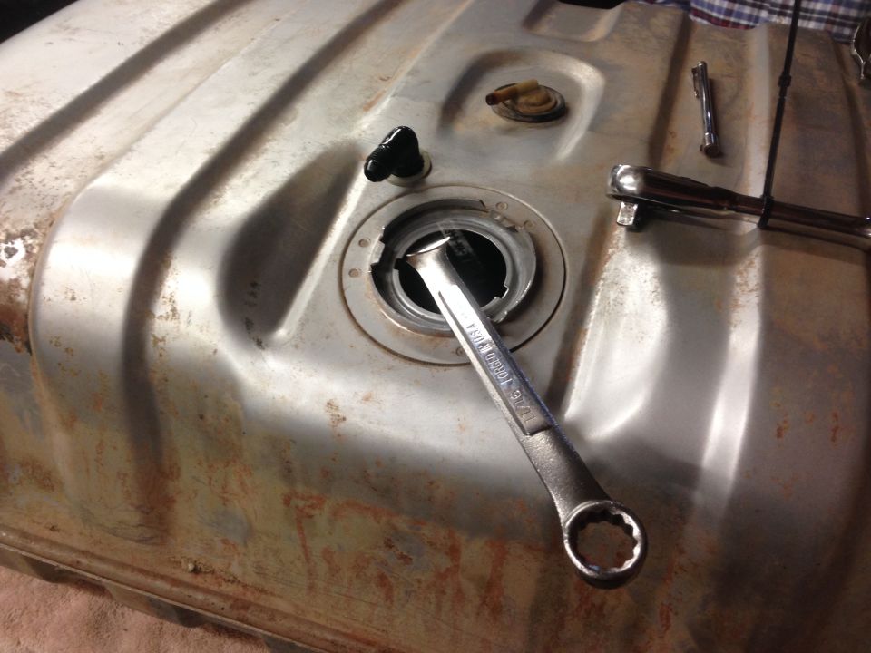 Close-up of a rusty fuel tank with a wrench on the filler neck