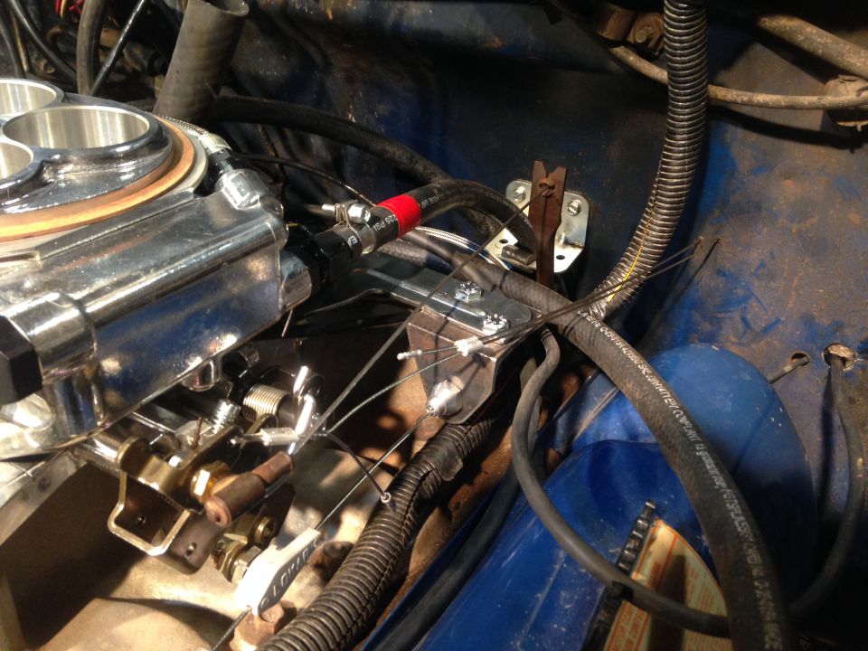 Close-up of a chrome carburetor and fuel lines in an engine bay