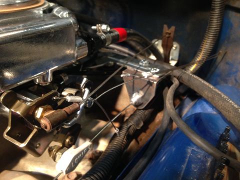 1979 Ford Bronco - Detail shot of the throttle cable and linkage assembly connected to the carburetor in an engine bay.