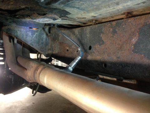 1979 Ford Bronco - Close-up view of a vehicle's exhaust system and frame, showing rust and an installed oxygen sensor.