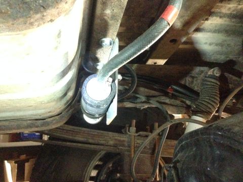 1979 Ford Bronco - Close-up view of a fuel filter being installed on the underside of a vehicle.