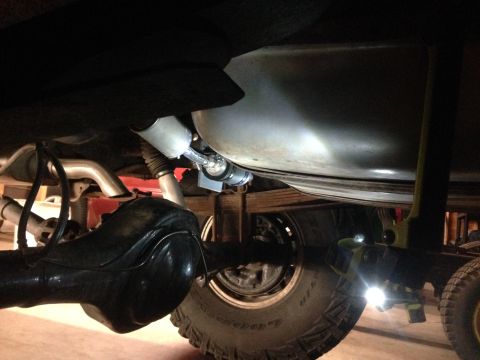 1979 Ford Bronco - The underside of a vehicle is shown, focusing on the fuel tank and rear axle components during installation.