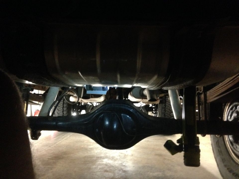 Underside of vehicle showing rear differential, fuel tank, and suspension components
